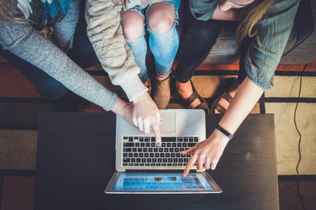 3 Menschen von oben die einen Computer nutzen
