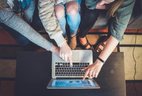 3 Menschen von oben die einen Computer nutzen