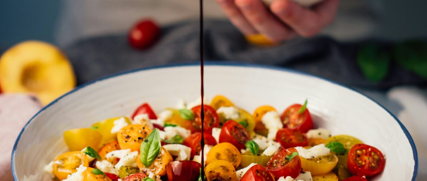 Jemand lässt Dressing in eine Salatschüssel laufen