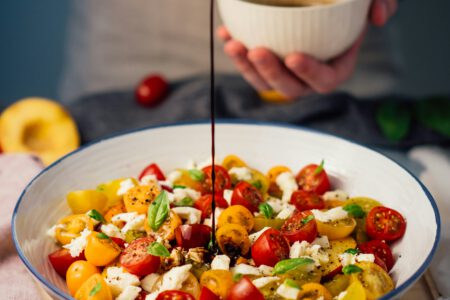 Jemand lässt Dressing in eine Salatschüssel laufen